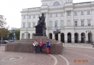 Dziewczynki przed pomnikiem w centrum Warszawy.