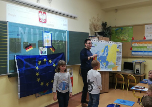 Dzieci i nauczyciel przy fladze UE.