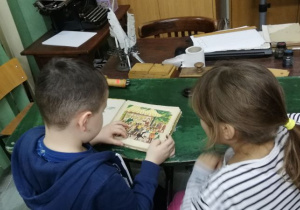 Dzieci oglądają dawne książeczki.
