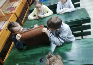 Dzieci oglądają stare przybory szkolne.