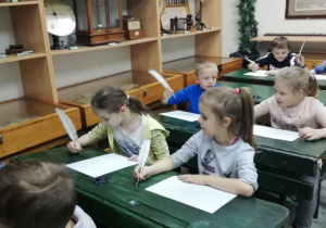 Dzieci piszą piórem.