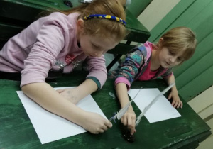 Dziewczynki próbują pisać piórem.