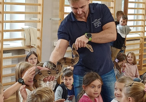 Uczniowie dotykają węża pod okiem prowadzącego pokaz.