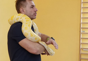 Prowadzący pokazuje węża, trzymając go owiniętego wokół swojej szyi.