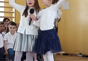 Dwie uczennice z klas pierwszych śpiewają piosenkę.