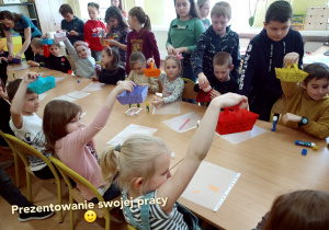 Przy stole dzieci prezentują swoje prace.