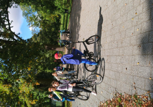 Uczniowie na rowerach w parku.