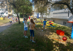 Dzieci ćwiczą przed budynkiem przedszkola.