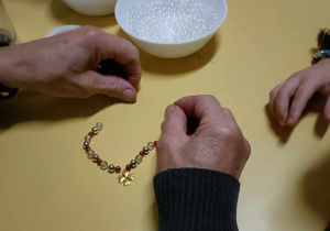 ręce kobiety torzące naszyjnik z koloroych kuleczek