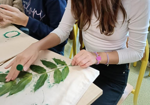 Uczniowie przygotowujący torby płócienne ozdobione liśćmi i roślinami