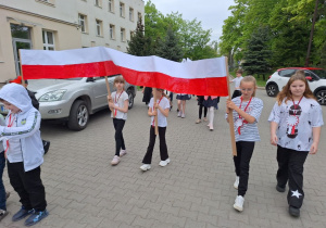 Uczniowie maszerują z flagą.