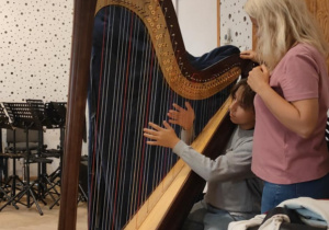 Uczeń klasy 6d poznaje tajniki gry na harfie podczas warsztatów muzycznych w Teatrze Wielkim w Łodzi.