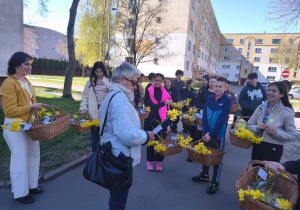 Uczniowie wręczają żywe żonile.